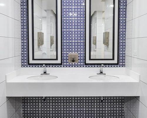 卫生间梳妆台配有双水槽和镜子. 白色、蓝色和深灰色瓷砖表面.